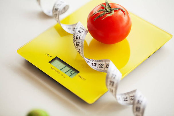 Concepto de dieta o control de peso. Frutas y verduras con cinta métrica en la escala de peso. Concepto de Fitness y Alimentación Saludable
 - Foto, imagen