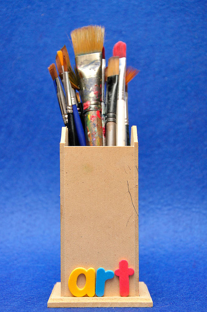 A collection of different size paint brushes in a wooden container with the word art - Photo, Image
