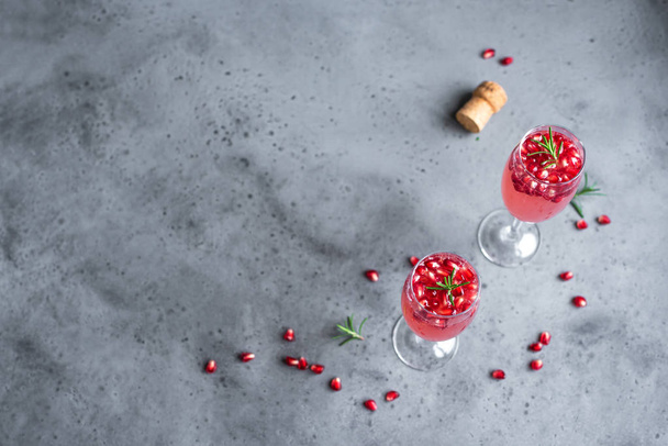 Pomegranate Champagne Mimosa Cocktail (Mocktail) with rosemary on concrete background, copy space. Mimosa Drink for Valentine Day or other holidays. - Foto, Imagen