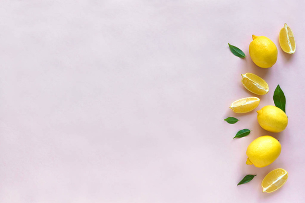 Lemons with green leaves on pink pastel background, top view, copy space. Organic fresh citrus fruits lemons, minimal conceptual flat lay. - Fotó, kép