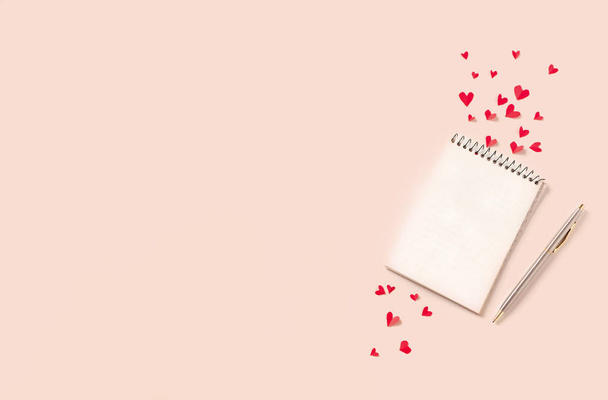 Notebook and red hearts isolated on beige background, copy space. Minimal flat lay with planning for Valentine day, love and romance concept, top view. - Photo, image