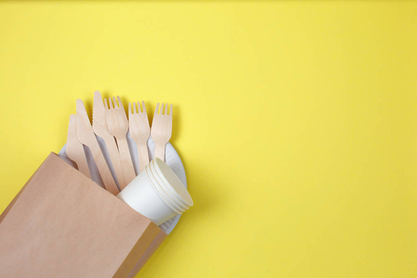Eco-friendly disposable utensils made of bamboo wood and paper on yellow background. - Fotografie, Obrázek