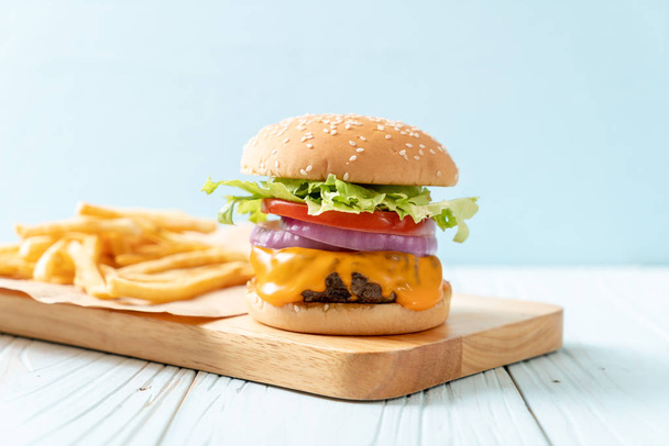 fresh tasty beef burger with cheese and french fries on wood background - Foto, immagini