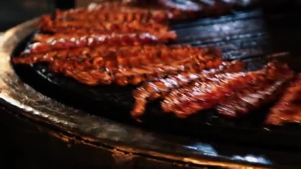 Video von fetten und öligen Schweinerippchen, die auf einer sich drehenden Grillmaschine in einem ukrainischen Fleischrestaurant gekocht werden.footage von köstlichen Speisen, die auf einer Grillmaschine in Nahaufnahme zubereitet werden - Filmmaterial, Video