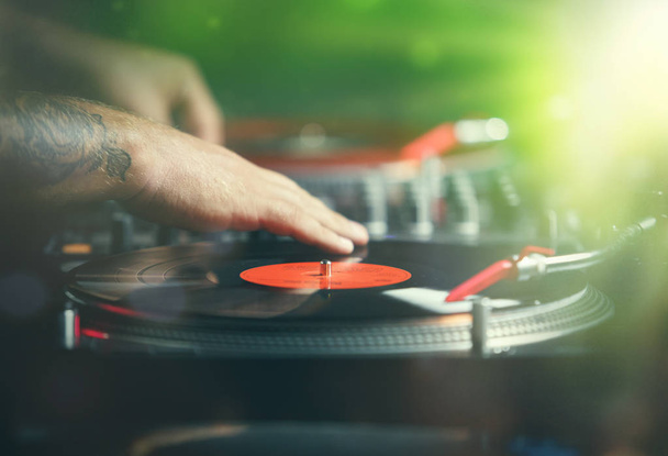 Hands of professional club dj scratching vinyl disc on turn table player device.Retro djs audio equipment in use on concert stage.Party disc jockey plays live set with analog records with music - 写真・画像