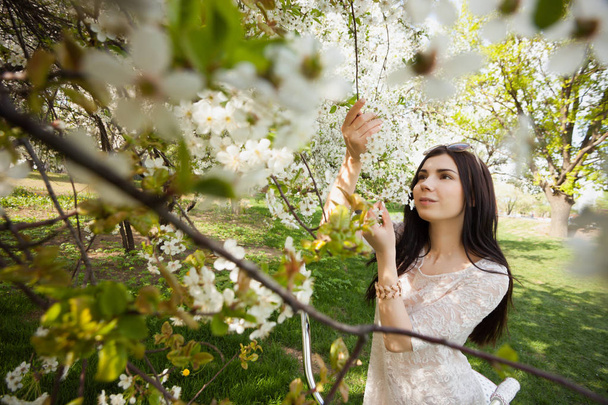Attractive young woman posing with lilic flowers in green park at bright spring day in her leisure time. Great portrait of beautiful girl loving nature.  - Photo, image