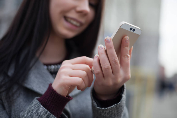 Mujer joven usando un teléfono inteligente moderno con cámara dual
 - Foto, imagen