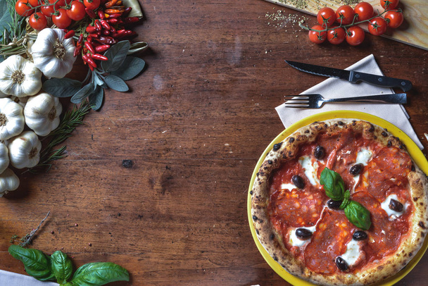 Top view backgound pizza napoletana con salame, salame, olive nere, formaggio e basilico. composizione cornice con ingredienti spazio libero per testo
 - Foto, immagini