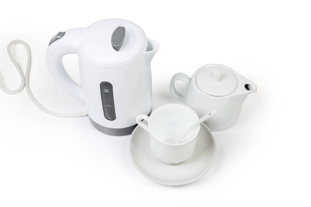 Küçük beyaz elektrikli su ısıtıcısı, Çaydanlık ve Seramik çay kaşığı beyaz bir arka plan üzerinde uçan daire üzerinde boş fincanla - Fotoğraf, Görsel
