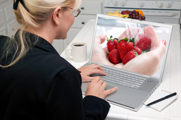 Tyttö käyttää kannettavaa tietokonetta hedelmiä näytöllä
 - Valokuva, kuva