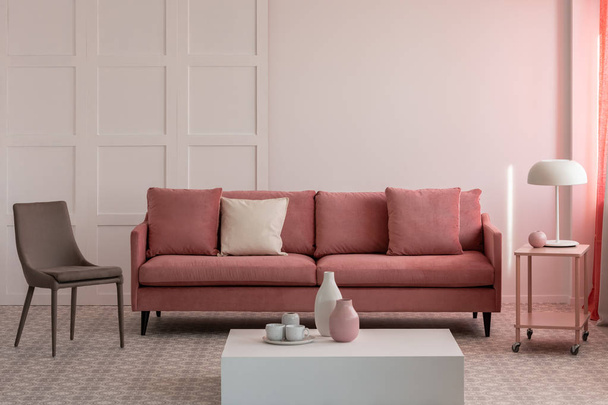 Stylish living room interior with pastel pink velvet sofa with pillows and trendy grey chair - Fotoğraf, Görsel