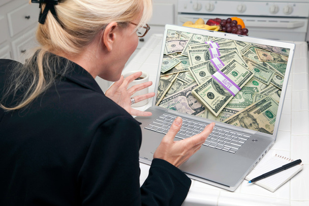 Mujer emocionada en la cocina usando el ordenador portátil para ganar o ganar dinero
 - Foto, imagen
