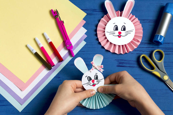 Child makes bunnies out of paper for Easter decoration. Creative idea for children's party. DIY concept. Step by step photo instruction. Step 15. Glue bunny head  - Foto, imagen