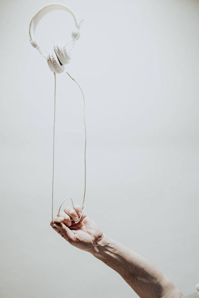 Auriculares y mano sobre fondo blanco
 - Foto, imagen