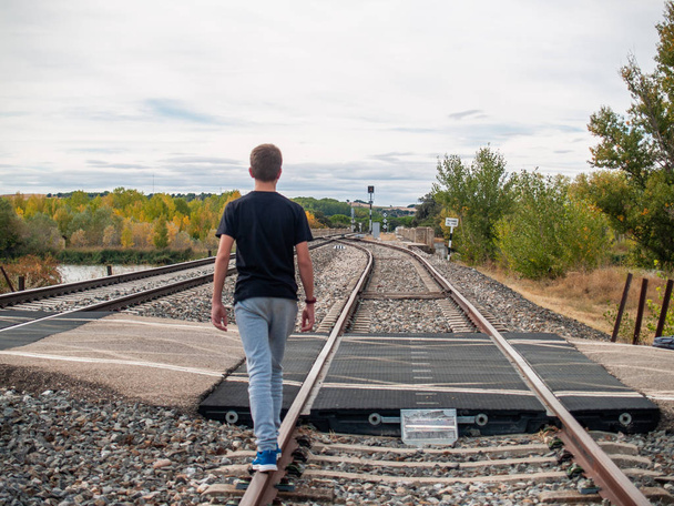 Мальчик-подросток идет по железнодорожным путям
 - Фото, изображение