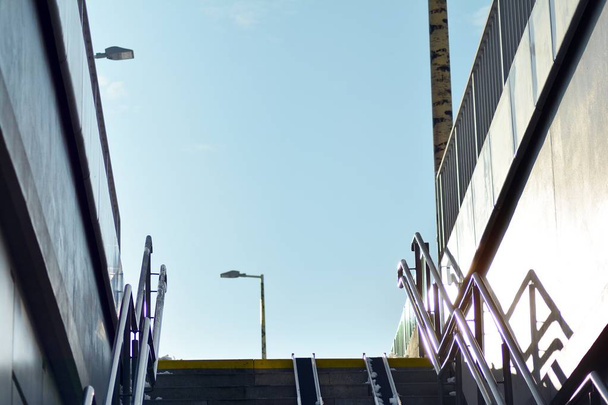 Фрагмент ступенчатого подъема к пешеходному мосту между платформами железнодорожного вокзала - Фото, изображение