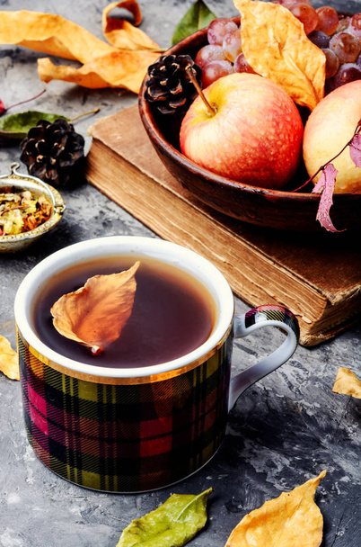 Cup with tea on autumn background of fallen leaves and apples.Autumn still life - Photo, Image