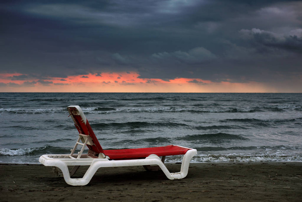 Espreguiçadeira vermelha no fundo do mar ao pôr-do-sol. Paisagem. A disparar à luz do dia. Retoque do autor
 - Foto, Imagem