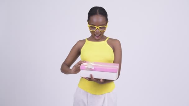 Happy young beautiful African woman opening gift box and looking surprised - Video