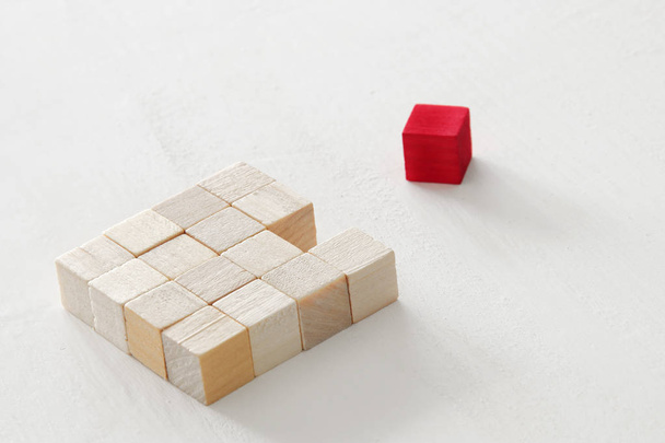 One different red cube block among wooden blocks. Individuality, leadership and uniqueness concept. - Photo, image