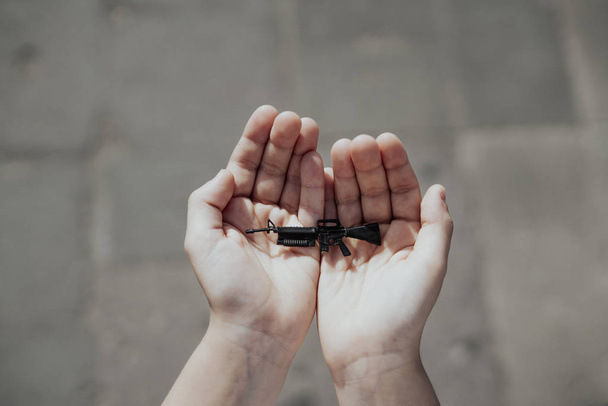 Arma de fuego miniatura en las manos de un niño
 - Foto, imagen