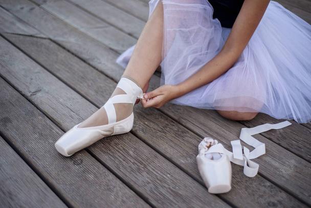 Молодая балерина завязывает пуанты
 - Фото, изображение