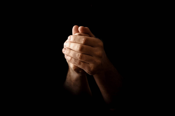 Men's hands in prayer on a black background. The concept of faith, prayer, mourning, forgiveness, confession. - Photo, image