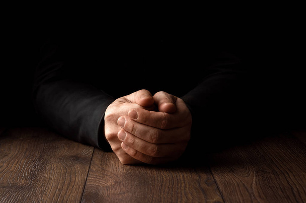 Men's hands in prayer on a black background. The concept of faith, prayer, mourning, forgiveness, confession. - Φωτογραφία, εικόνα