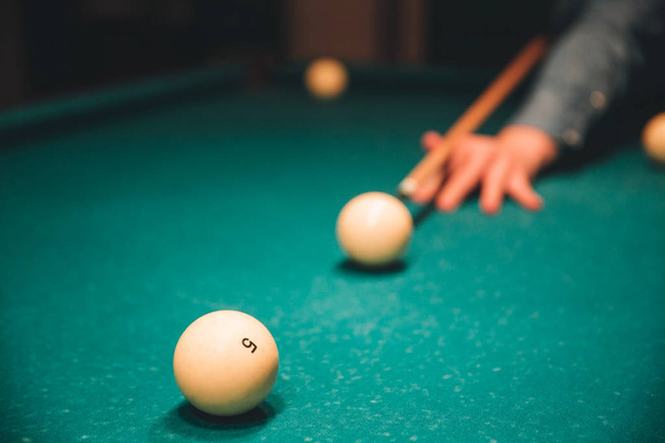 Picture of mans hand holding billiard cue and aiming to breal ball. he plays inside on bed of table. - Φωτογραφία, εικόνα