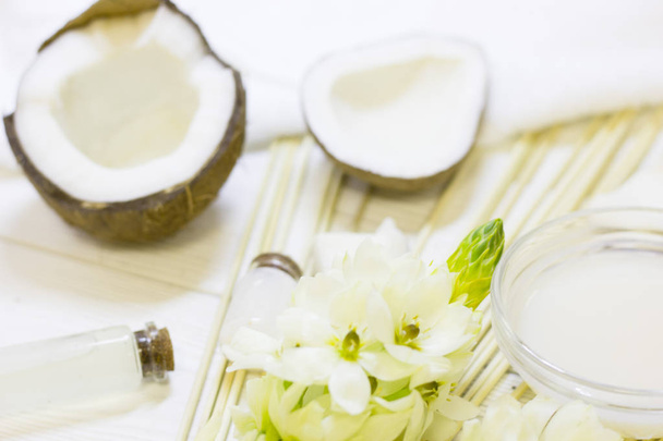 Natuurlijke kruiden huid verzorgingsproducten, bovenaanzicht ingrediënten kokosnoot essentie olie en bloem concept van de beste alle natuurlijke gezicht moisturizer. Gezichtsbehandeling voorbereiding achtergrond - Foto, afbeelding