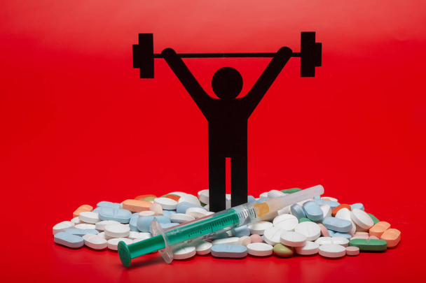 Gewichtheben-Piktogramm mit Pillen und rotem Hintergrund - Foto, Bild