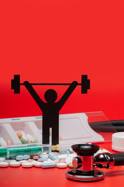 Gewichtheben-Piktogramm mit Pillen und rotem Hintergrund - Foto, Bild