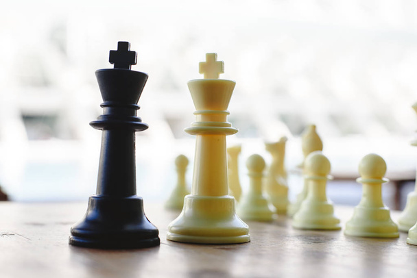 Musta ja valkoinen shakki kuninkaat kohtaavat välillä defocused kappaletta puulevyllä
. - Valokuva, kuva