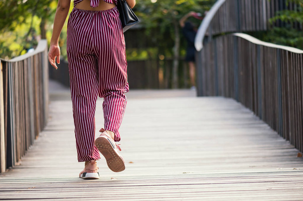 Lähemmäs hipsterinainen kävelee puistossa. Matkustaa kesällä käsite. Fashionista tyttö puutarhassa kopioi tilaa tekstiä
. - Valokuva, kuva