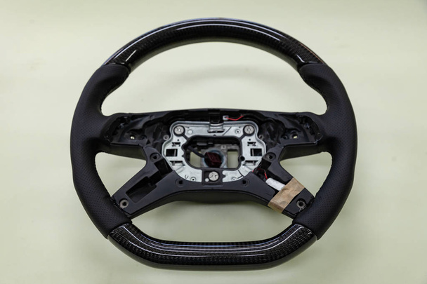 Lenkung des Autos vor der Montage demontiert - Carbon-getuntes schwarzes Rad mit perforiertem Leder. - Foto, Bild