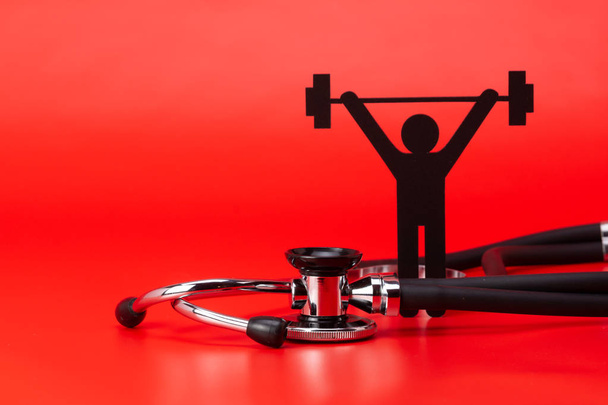 Pictograma de levantamiento de pesas, Estetoscopio, primer plano aislado con fondo rojo
 - Foto, imagen
