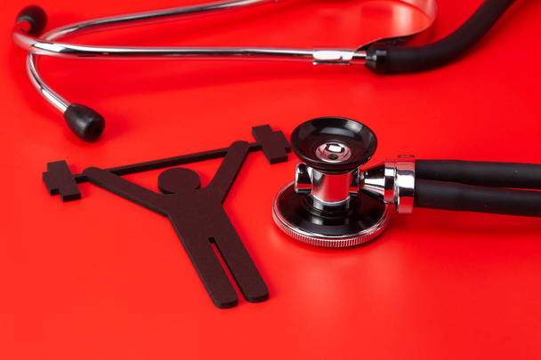 Weight lifting pictogram, Stethoscope, close-up isolated with red background - Photo, Image