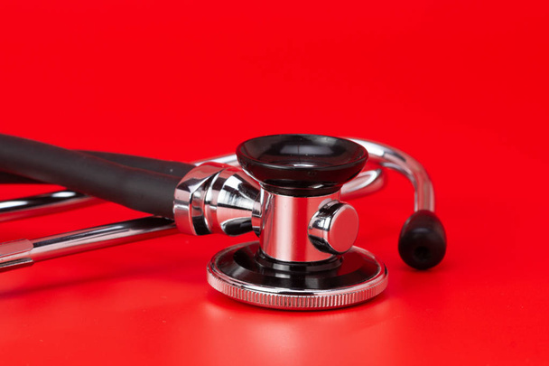 Stethoskop, medizinisches Instrument, Nahaufnahme isoliert mit rotem Hintergrund - Foto, Bild