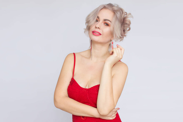 Beauty portrait of attractive blonde woman with bright makeup wearing red dress posing isolated over white background - Zdjęcie, obraz