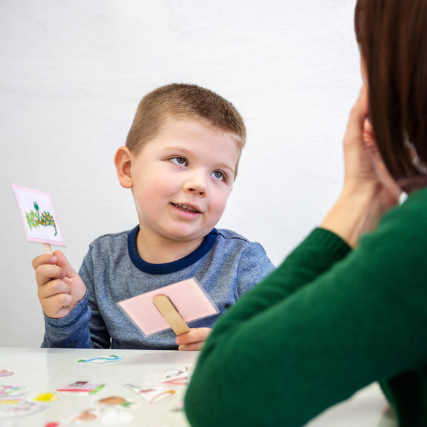 Young boy in speech therapy office. Preschooler exercising correct pronunciation with speech therapist. Child Occupational Therapy Session. - Фото, изображение