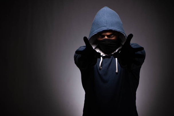 Young gangster in hood on grey background  - Фото, зображення