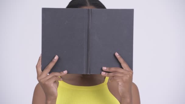 Young beautiful African woman hiding behind book - Metraje, vídeo