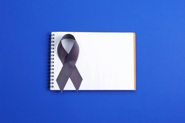 Brain cancer grey color awareness ribbon isolated on blue background - Fotó, kép