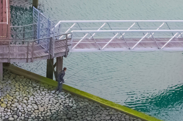 ψαράς στέκεται το ανάχωμα στη θάλασσα με ένα καλάμι ψαρέματος, ψάρι άθλημα στο λιμάνι - Φωτογραφία, εικόνα