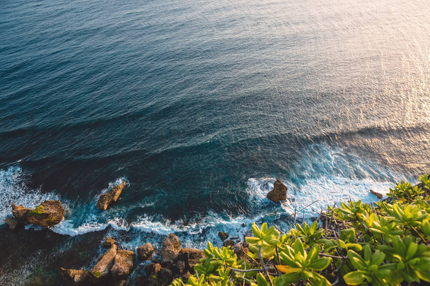 Блакитний океан з хвилями, камінням і скелею
 - Фото, зображення
