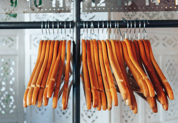Wooden hangers and stainless steel hook were hanging on the row - Photo, Image