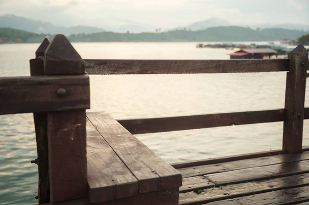 Houten zitbank met prachtige brug natuurlijke ochtend zonsopgang boven de Songkalia rivier achtergrond op Saphan Mon houten brug (Mon brug), Thailand-langste houten, Sangkhlaburi, Kanchanaburi, Thailand. - Foto, afbeelding