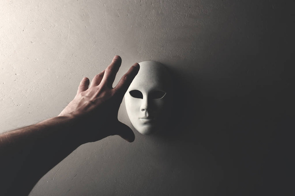 ruka s bílou maskou visí na zdi - Fotografie, Obrázek