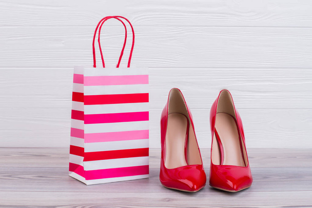 Red stilettos and paper gift bag. - Fotografie, Obrázek