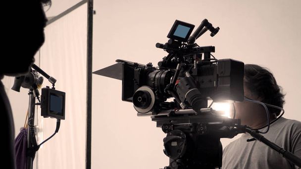 За съёмками или съёмками видео съемочной группы и съемочной группы настраивается камера на штативе и профессиональное оборудование в студии для офлайн ТВ коммерческой или онлайн-записи веб-фильмов. - Фото, изображение